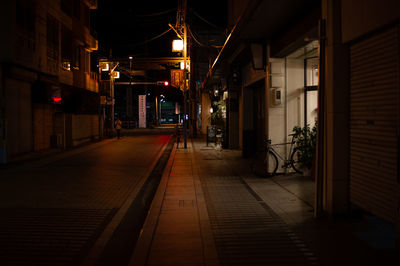 Empty alley amidst buildings at night