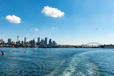 View of city at waterfront against cloudy sky