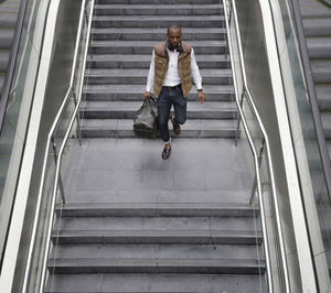 High angle view of man with bag walking on steps at subway station