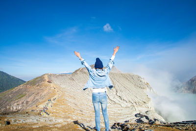 Rear view of person standing on mountain against sky