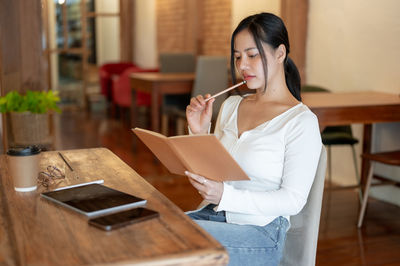 Young woman using mobile phone while sitting at home