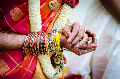 Midsection of bride with henna tattoos on hands