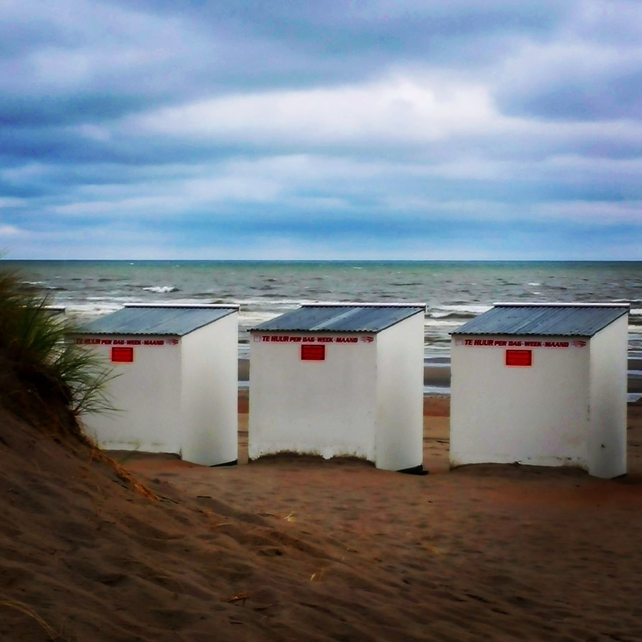 BEACH HUT ON SHORE AGAINST SKY