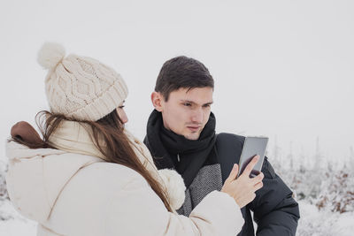 A young guy looks at a photo on the phone in the hands of a girl.