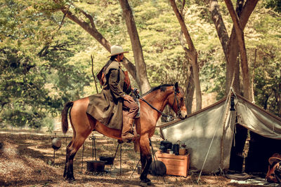 Side view of man sitting on horse in forest