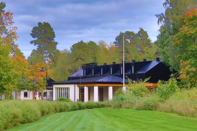 House amidst trees and buildings against sky during autumn