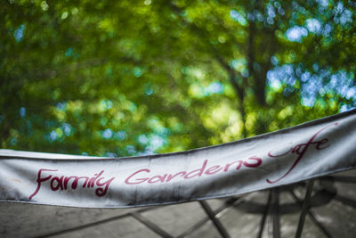 Close-up of text on railing against trees