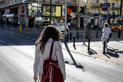 Rear view of woman walking on road in city