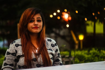 Portrait of young woman in city at night