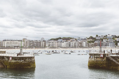 Boats in sea against cloudy sky