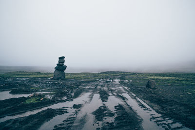 Wet dirt road leading towards sea in foggy weather