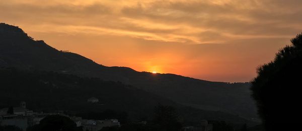 Scenic view of silhouette mountains against orange sky