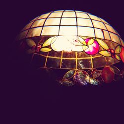 Low angle view of illuminated lighting equipment against black background