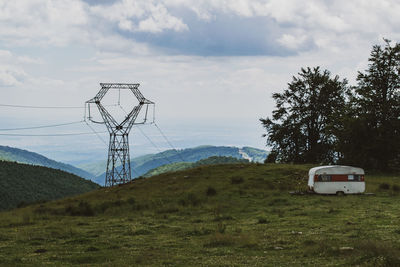 Trailer on field against sky near power line