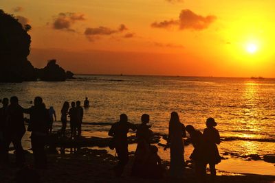 Silhouette people on beach against sky during sunset