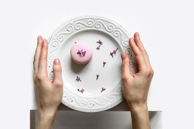 Cropped hands of woman holding apple against white background