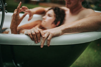 Midsection of shirtless woman with arms raised