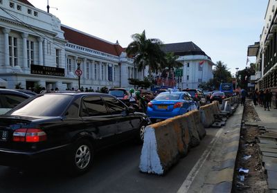 Cars on city street by buildings against sky