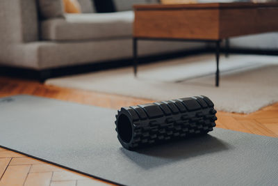 High angle view of black foam roller and a fitness mat, modern living space, selective shallow focus