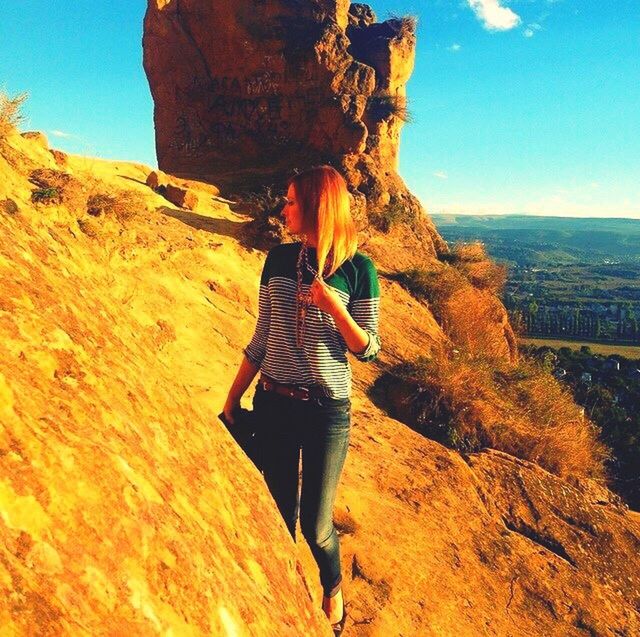 leisure activity, lifestyles, sunlight, mountain, sky, low angle view, rock - object, men, full length, standing, outdoors, clear sky, photography themes, nature, holding, photographing, human representation, sunbeam