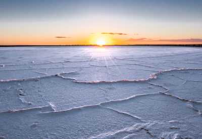 Scenic view of salt flat against sky during sunset