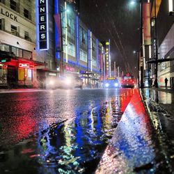 Illuminated city street during rainy season at night