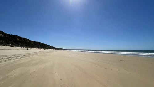 Scenic view of beach against clear blue sky
