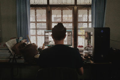 Rear view of man sitting at window