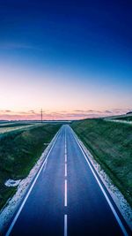 Road passing through landscape against sky during sunset