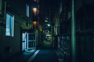 Empty street amidst buildings in city at night