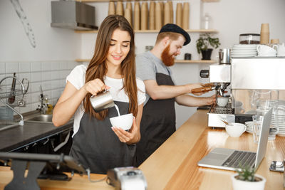 Young man and woman using laptop in kitchen