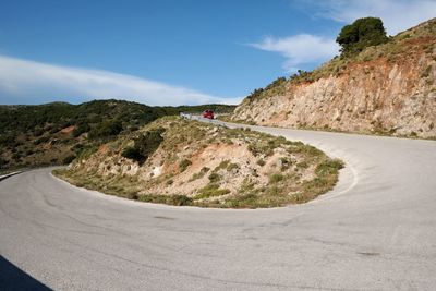 Scenic view of road by mountains against sky