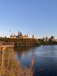 View of buildings by river against clear sky