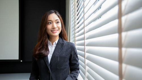 Portrait of young woman standing against wall