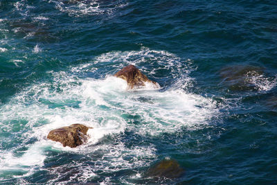 High angle view of waves splashing on rocks