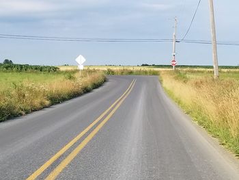 Empty road by landscape against sky