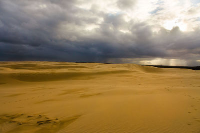 Scenic view of desert against dramatic sky