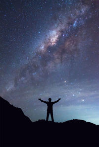 Silhouette of man standing against star field at night