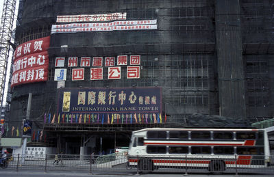 Low angle view of information sign on scaffolding building by bus on road