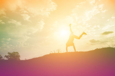 Silhouette woman standing on shore against sky during sunset