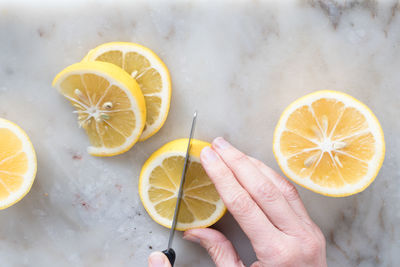 Cropped image of hand cutting lemon on table