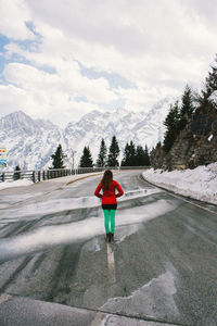 Rear view of person walking on snowcapped mountain against sky