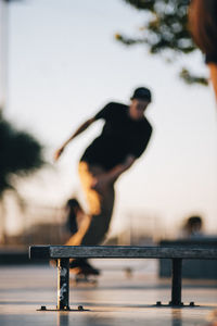 Man skateboarding at skateboard park with bench in foreground