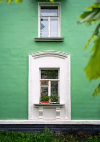 Window on white wall of house. white window on the green wall. bright facade of residential building