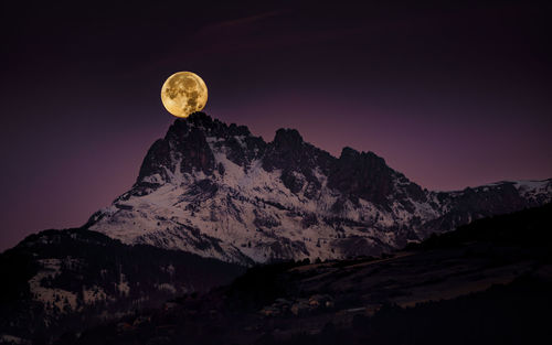 Scenic view of snowcapped mountains against sky at night and the big red full moon