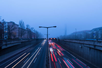 Light trails on road against clear blue sky