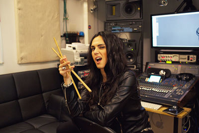 Young woman holding drumsticks in a recording studio