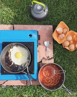 Directly above shot of breakfast with camping stove on grassy field