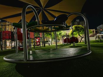 Empty park by street in city at night