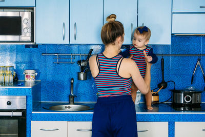 Young mother holding cute baby daughter in kitchen. happy family mother and baby toddler girl